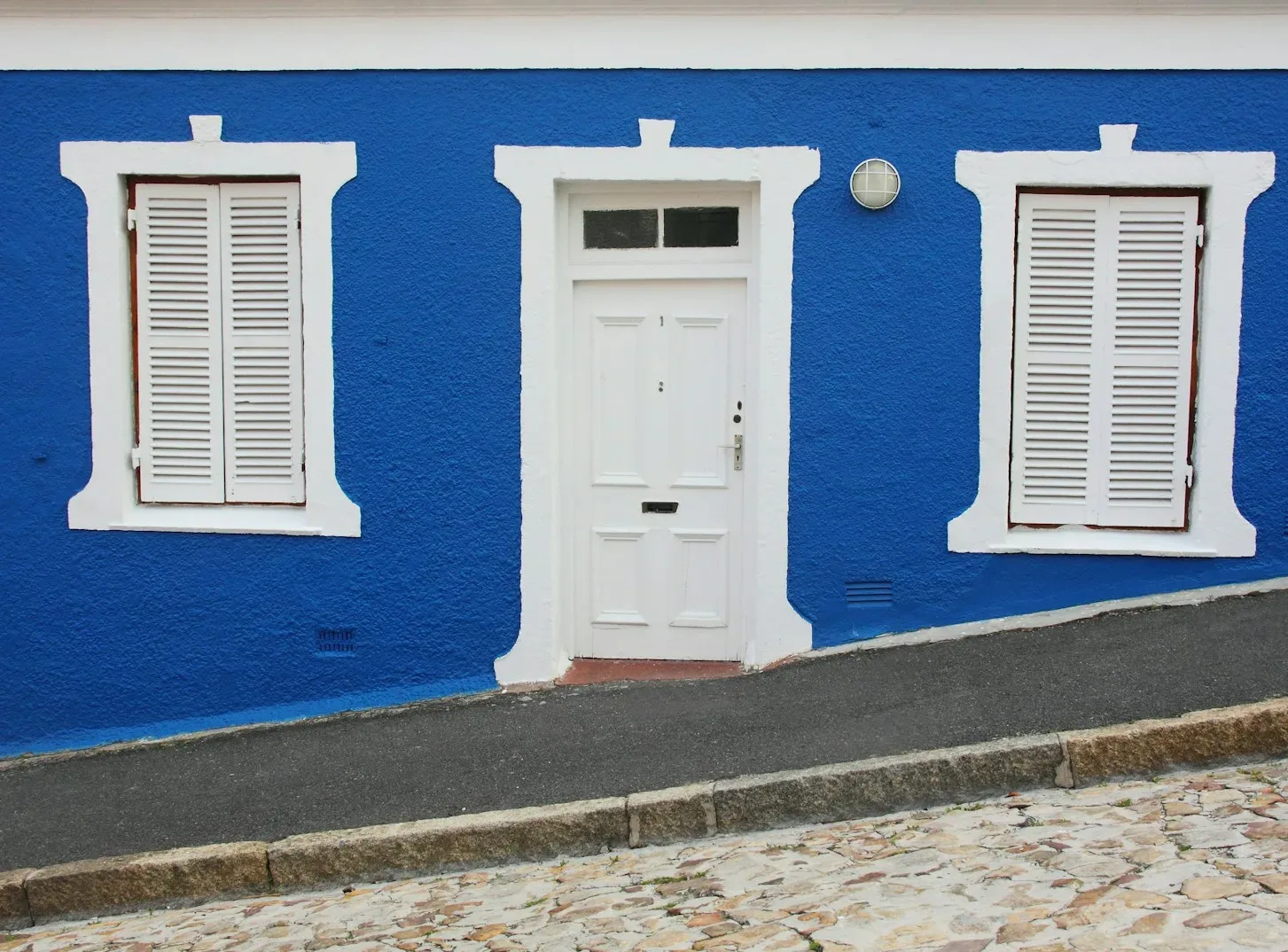 white wooden door on blue concrete wall